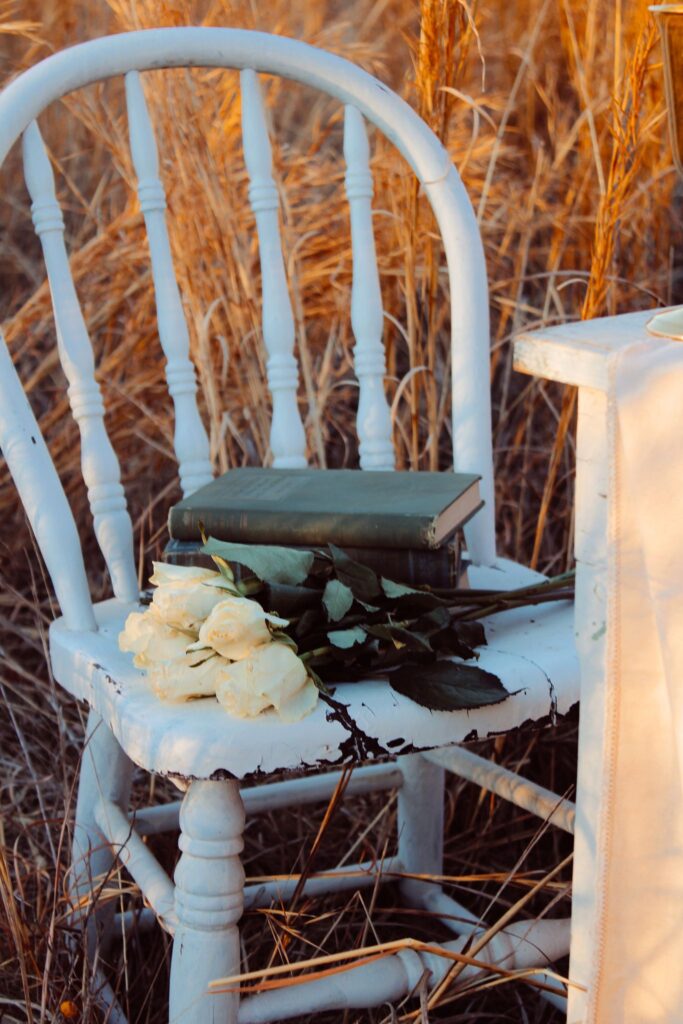 Vintage white chair with roses and stack of green book.