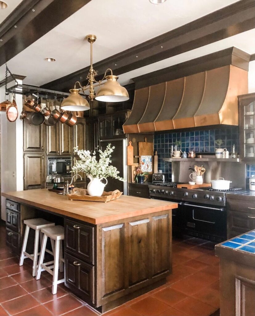 Large country kitchen with copper hood and professional stove.