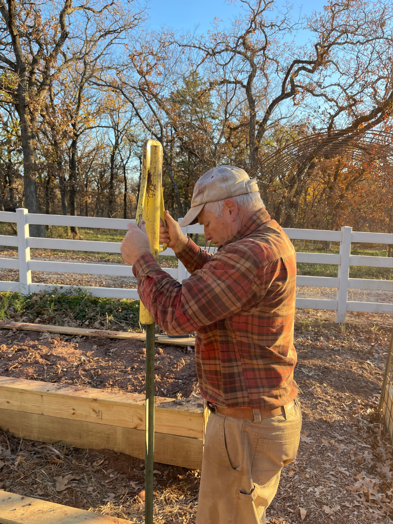 Setting the fence post at the corner of the raised bed.