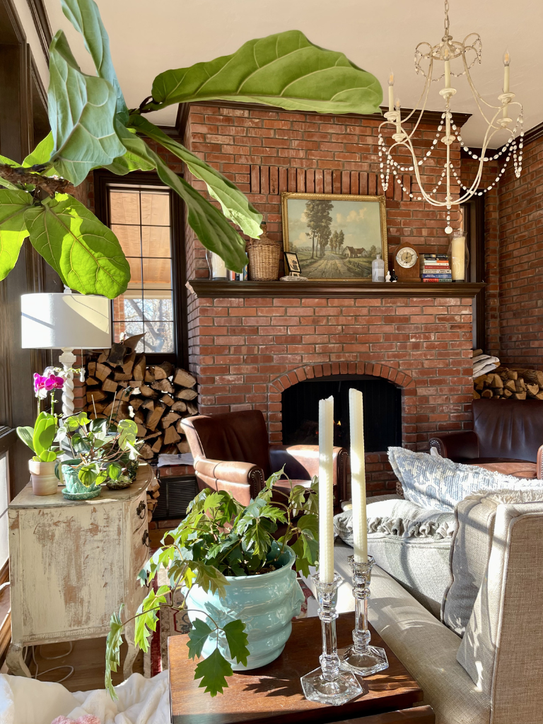 A vintage inspired keeping room with a brick fireplace and chandelier